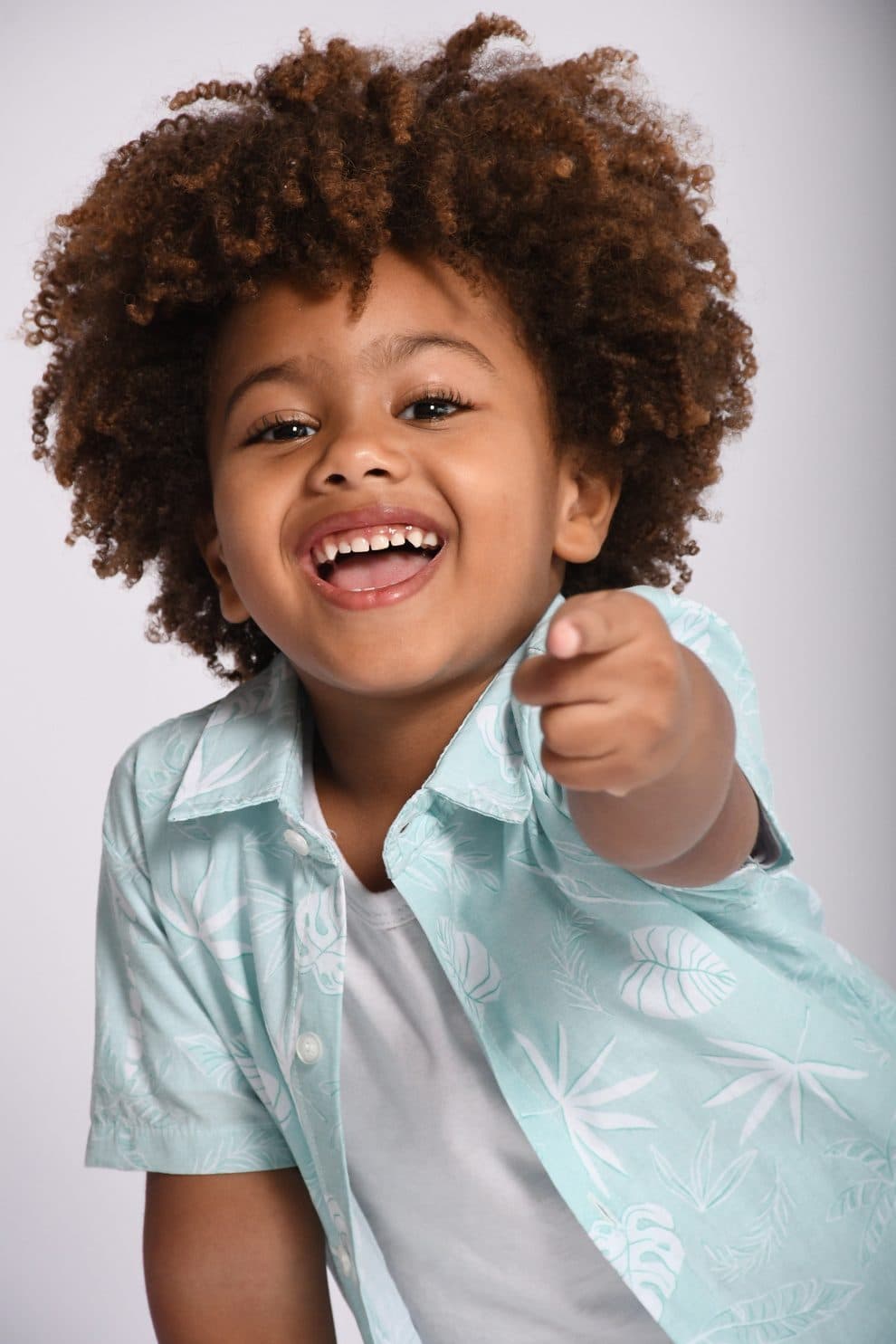 Isaac Roberto sorrindo e apontando, em camisa floral