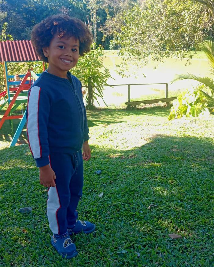 Isaac Roberto de moletom azul-marinho, num parque com playground ao fundo