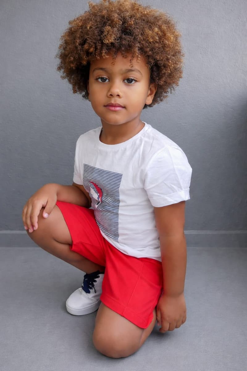 Isaac Roberto agachado, de camiseta branca e shorts vermelho