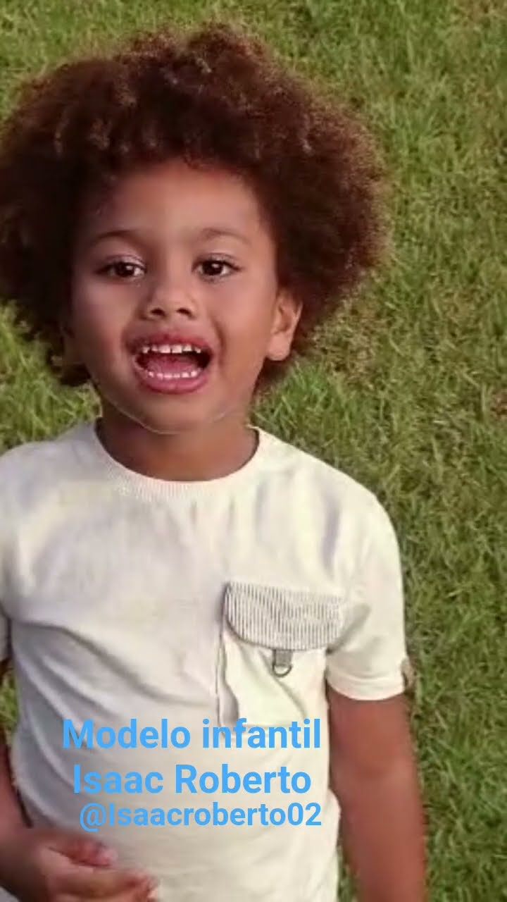 Isaac Roberto deitado na grama, sorrindo e falando com a câmera
